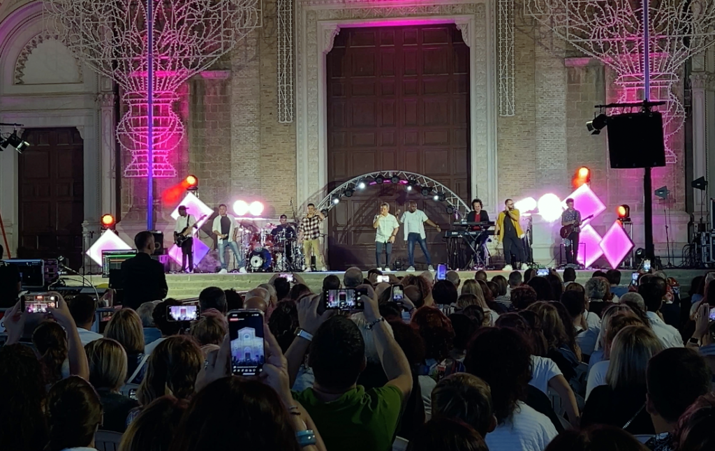 Giovedì sera, il sagrato del Duomo Tonti di Cerignola è stato il palcoscenico di un evento emozionante, che ha visto protagonisti i Gen Rosso, celebri per la loro musica ispirata ai valori della pace e della solidarietà. La piazza, illuminata dalle tradizionali luminarie della festa patronale in onore di Maria SS.ma di Ripalta, si è riempita di un pubblico entusiasta che ha ballato e cantato a ritmo di musica.